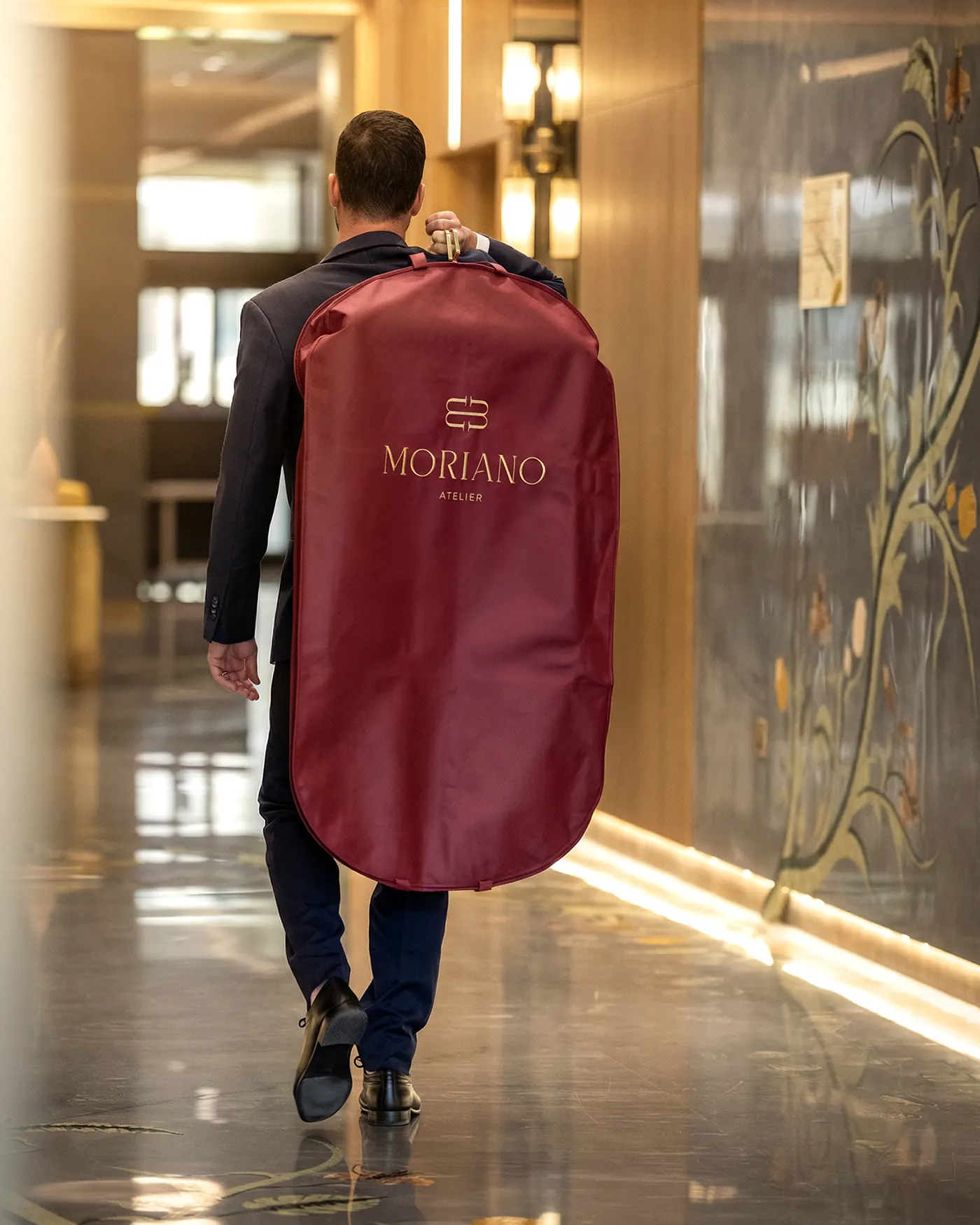 A finished commission carried through the atelier in its garment bag