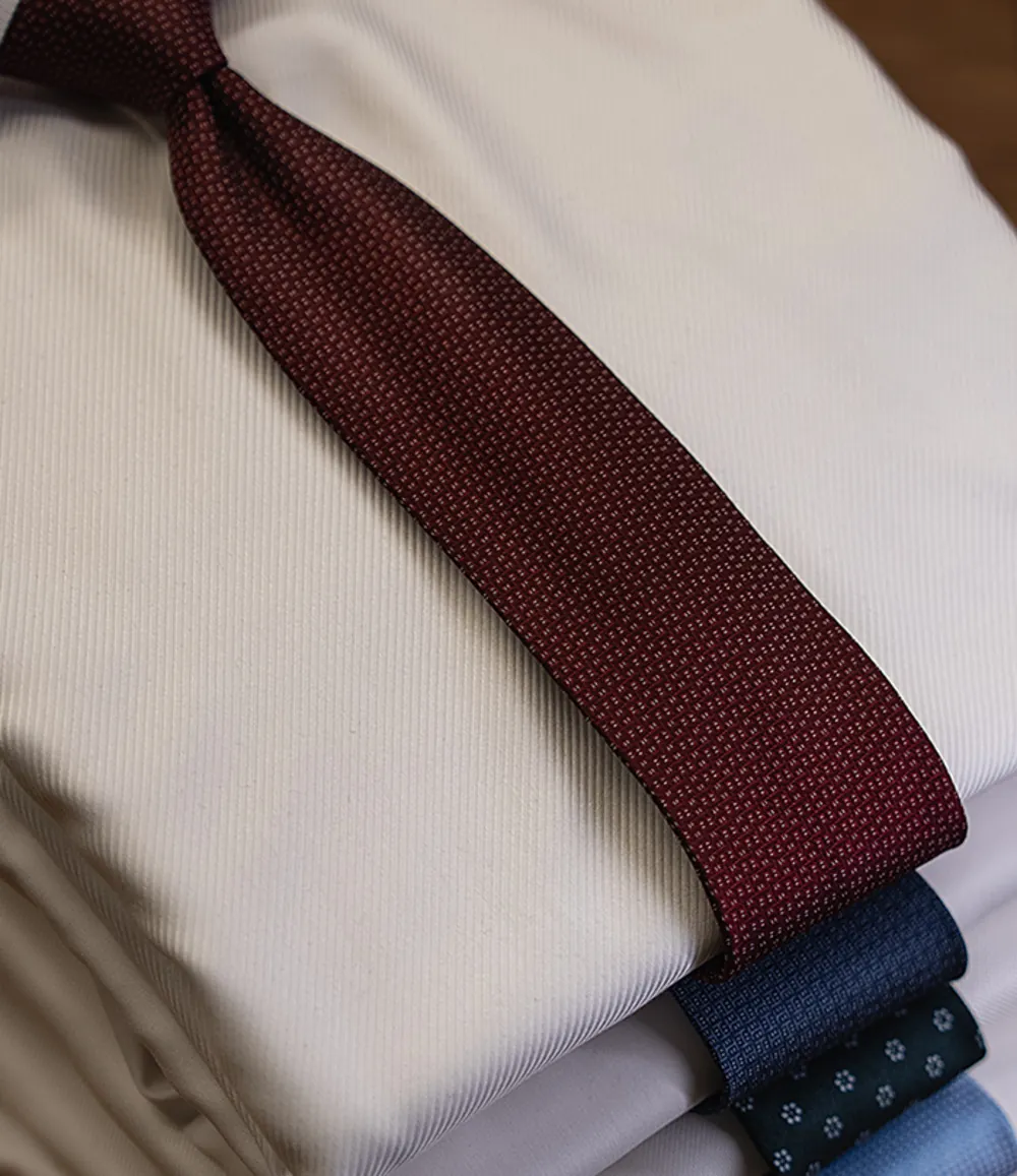 A silk tie on folded shirts at the Atelier
